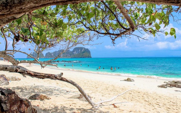 Koh Phi Phi Sunrise Escape: Bamboo & Khai Island Adventure. Tropical beach scene with turquoise water, white sand, and lush greenery. Gay travel.