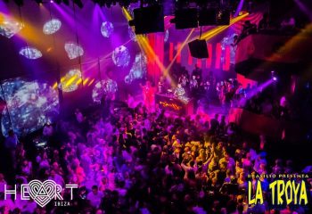 La Troya at HEART Ibiza gay club. A DJ plays for a large crowd under purple & yellow lights. Gay nightlife & travel advice.