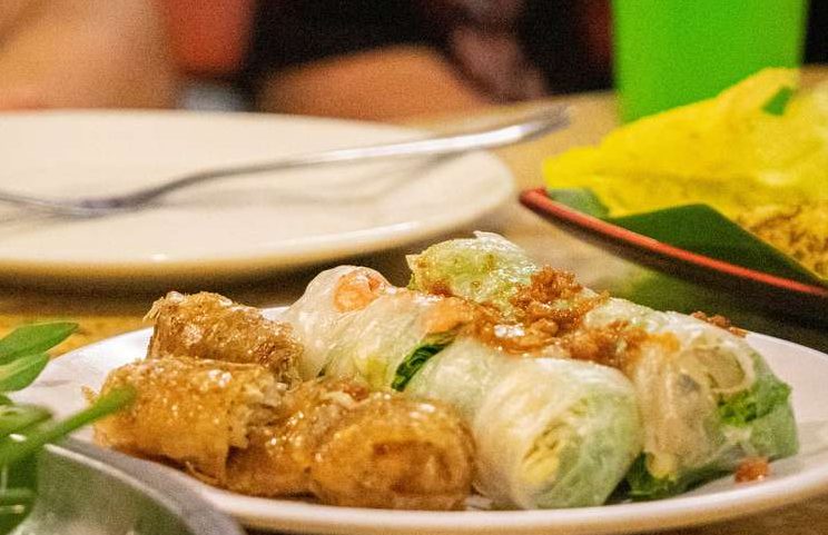 Hanoi Bites tour. Fresh spring rolls, fried spring rolls, and a yellow crepe on a plate. Gay-friendly food tour in Hanoi, Vietnam.