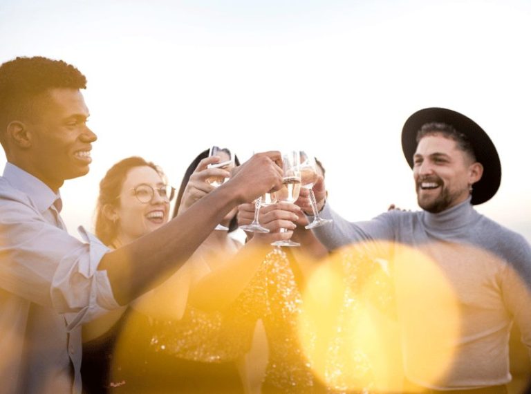 Lisbon Sunset Boat Party Cruise: Diverse group of friends toasting with champagne, enjoying iconic views and open bar. Gay travel adventure.