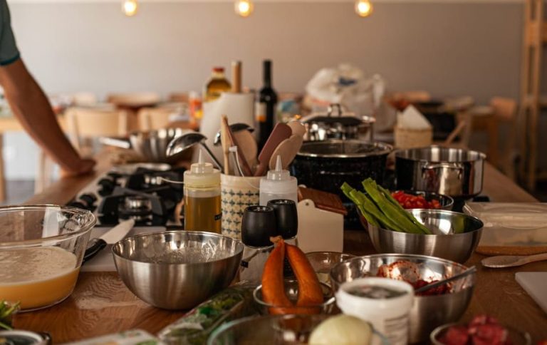 Lisbon cooking class: ingredients & utensils on a wooden table. Gay-friendly experience, traditional Portuguese cuisine. Wine, pots & bowls visible.