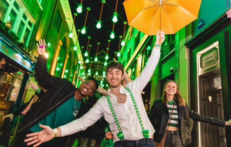 London Soho nightlife tour: People enjoying a bar crawl, celebrating St. Patrick's Day. Gay travel in London, festive atmosphere.