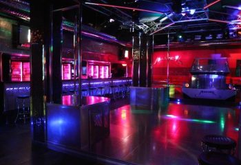 Interior of Mantrix Gay Club in Gran Canaria. Dance floor with bar, stage, and colorful lighting. Gay travel advice.