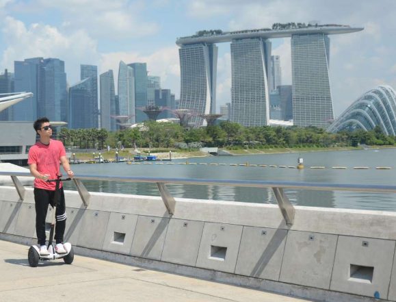 Gay man on a mini Segway tour in Singapore's Marina Bay. The Marina Bay Sands hotel and the city skyline are in the background.