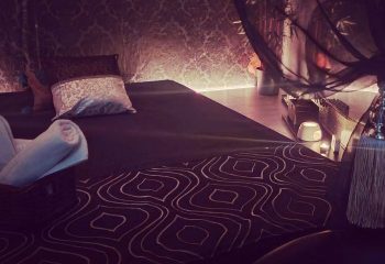 Gay massage in Madrid: Relaxing massage room at Majestic, featuring a massage bed with pillows, towels, and ambient lighting.