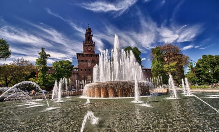 Milan's Sforza Castle: A Renaissance masterpiece. Fountain view, blue sky, and historic architecture. Gay travel destination, cultural tour.