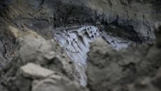 A layer of permafrost melts, exposing the rocky substrate underneath.