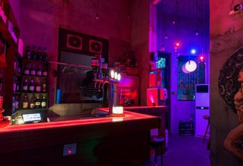 Interior of Moon Bar in Shanghai, a gay-friendly travel destination, featuring a bar with red lighting and a purple-lit doorway.