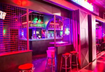 Entrance of Mykonos Gay Club in Gran Canaria, Spain. Disco balls, bar, and red stools are visible. Nightlife for gay men travelers.