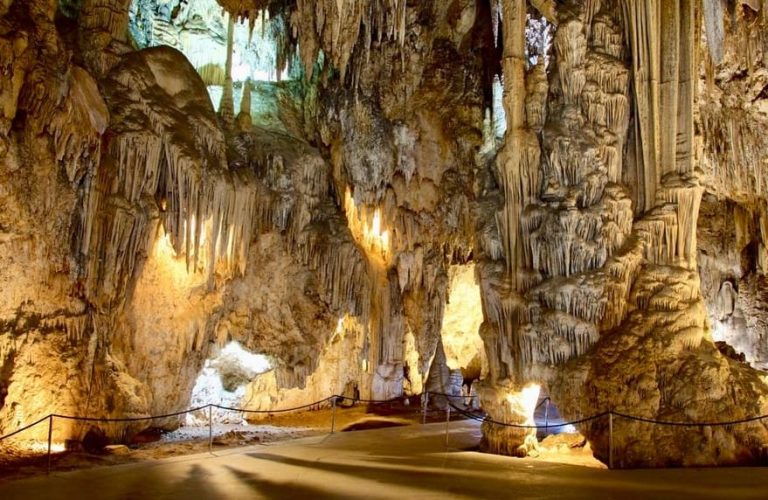 Nerja Caves, Spain. Stalactites and stalagmites in a vast cavern, illuminated by warm lighting. A tour through Spain's hidden gems.