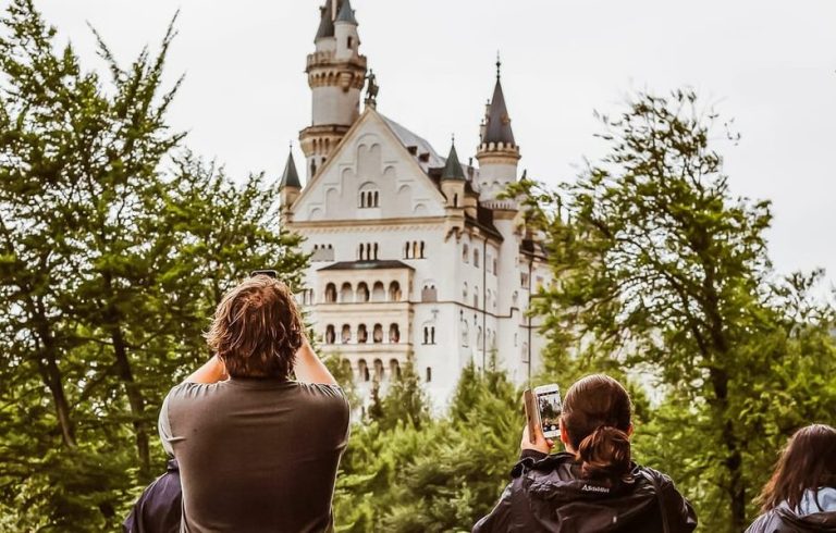 Neuschwanstein Castle day trip from Munich. Tourists photograph the fairy tale castle. Gay travel destination in Germany.