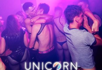 Gay club Unicorn London scene. Men dancing, kissing, and wearing underwear. Nightlife at gay bar with live DJ and dark orgy room.