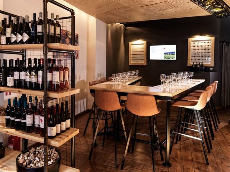 Athens wine tasting venue near the Acropolis. Shelves of wine bottles, tables set with glasses, and seating for a Greek wine experience.