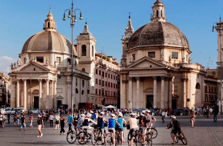 Rome E-Bike Tour: Group of gay travelers pedal through Piazza del Popolo. Iconic churches & hidden gems on a chic bike tour. Rome travel advice.