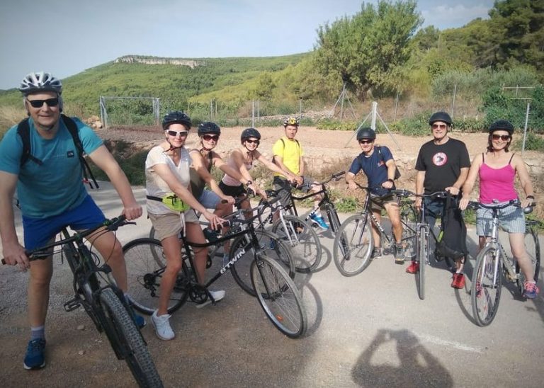 Gay group on Pedals & Pinot wine tour from Sitges. Cyclists with helmets pose on bikes. Outdoor adventure in Spain. Active travel.