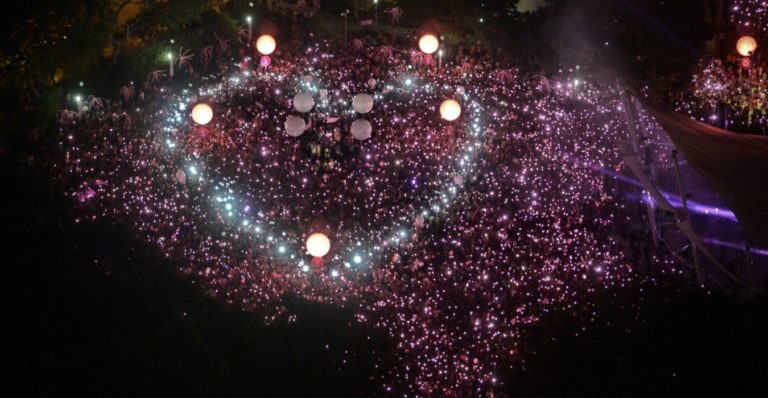 Pink Dot Singapore gay event. Aerial view of crowd holding lights forming a pink dot. Gay travel advice.