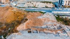 A large excavation site in the desert near a city