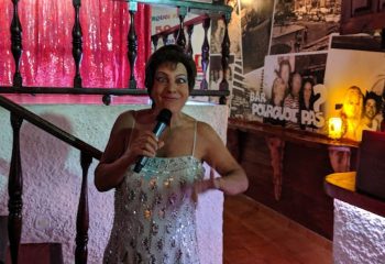 Drag performer at Pourquoi Pas, a gay bar in Torremolinos, Spain. The entertainer is wearing a sparkly dress and holding a microphone.
