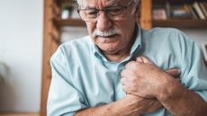 An older man clutches his chest in pain