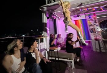 R7 Bar Hanoi: Drag queen performance at gay bar. Patrons watch as a performer in silver boots is lifted by a man for an aerial stunt.