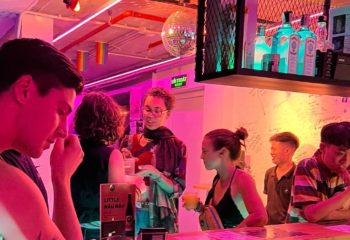 Gay travel: People at R7 Bar in Hanoi, Vietnam. Disco ball, rainbow flags, and pink lighting create a vibrant, inclusive atmosphere.