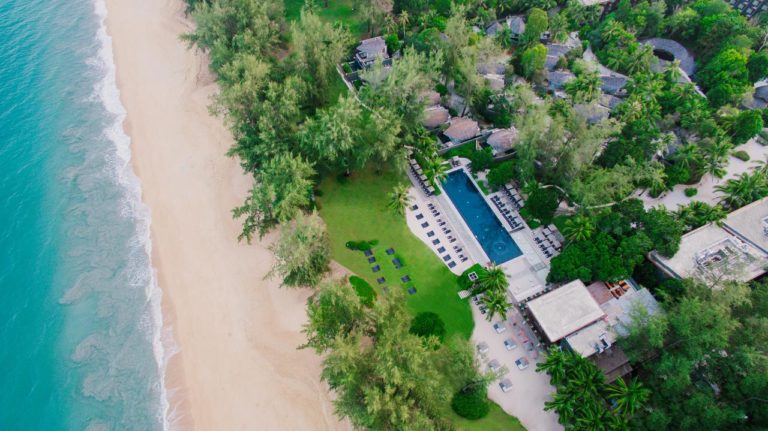 Aerial view of Renaissance Phuket, a luxury gay-friendly resort. Beach, pool, and lush greenery offer a relaxing vacation.