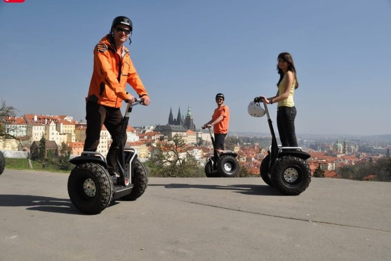 Gay-friendly Segway tour in Prague. People on Segways with Prague Castle in the background. Sightseeing and local stops on a Segway.