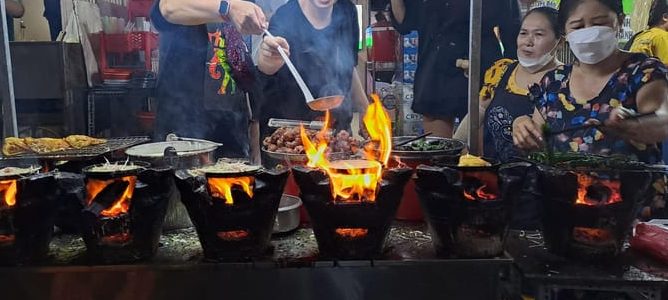 Hanoi Bites tour: Street food vendor cooking with flames. Street vibes in Ho Chi Minh. 11 tastings on a scooter food tour. Gay-friendly travel.