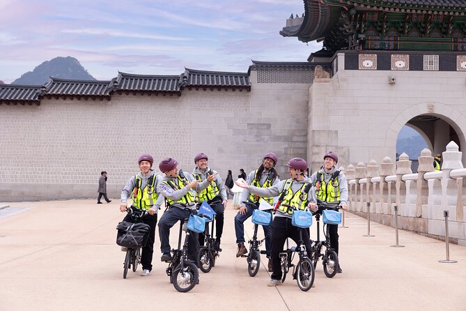 Gay men on Seoul E-bike Tour. Group of friends exploring Seoul, South Korea, on bikes. Seoul-Bike-Tour near historic architecture. Morning adventure.