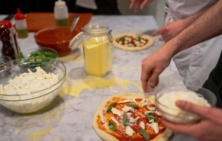 Rome's Hot Pizza Making Party: People prepare pizza with tomato sauce, mozzarella, and basil. Gay travel advice.