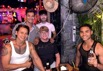 Gay travelers at Space Hair Salon and Bar, Phnom Penh. Group of smiling men enjoying drinks, nightlife in Cambodia. Gay travel destination.
