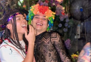 Gay travelers at Space Hair Salon & Bar, Phnom Penh. Man in rainbow wig smiles. Gay nightlife in Cambodia. LGBTQ+ travel.