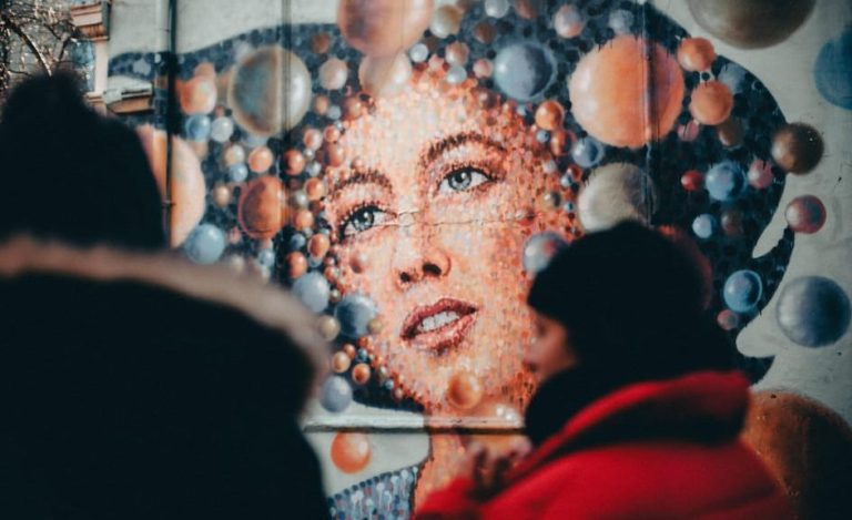 East London's graffiti walk through Shoreditch Brick Lane: Street art mural of a woman's face surrounded by colorful bubbles.