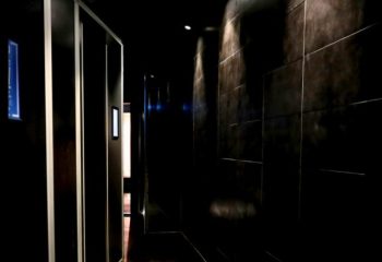 Interior of Sydney Sauna Darlinghurst, a gay sauna. Dark hallway with tiled walls and cubicles. Gay travel advice.