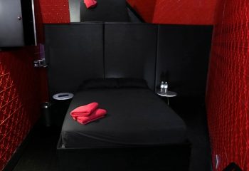 Sydney Sauna Darlinghurst private room. Black bed with red towels, red walls. Gay sauna lodging in Sydney, Australia.