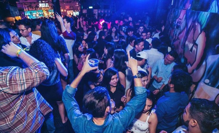 Taipei Gay-Friendly Pub Crawl: Crowded nightclub scene with people dancing and socializing under blue lighting. Nightlife activity.