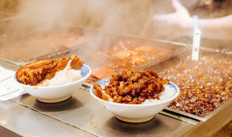 Taipei Night Market food tour: Bowls of steaming braised pork rice, a popular Taiwanese dish, at a street food stall. Gay-friendly Hanoi bites.