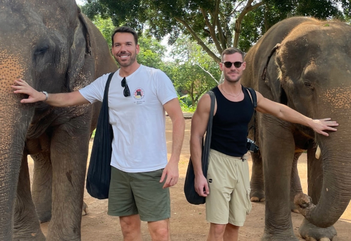 Gay couple exploring Koh Samui, Thailand, interacting with elephants. Steven's stories highlight ethical animal tourism for gay travelers.