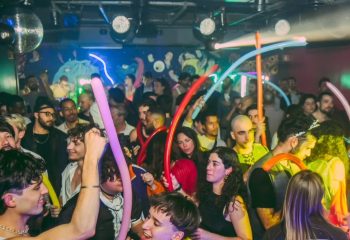 Gay men at Trumps Lisbon, a vibrant gay club in Portugal. Partygoers with balloons dance under disco lights. Gay travel nightlife scene.