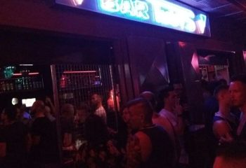 Crowded Tubos Gay Bar in Gran Canaria. Neon sign above the entrance. Gay nightlife scene. Gay travel destination.