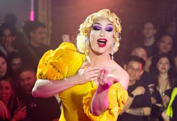 Drag queen in Sydney's Universal nightclub, a popular gay venue. She wears a yellow dress, blonde wig, & heavy makeup. Nightlife.