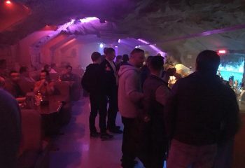 Up & Down gay bar interior. Men gather at the bar in a cave-like setting with purple lighting. Nightlife travel destination.