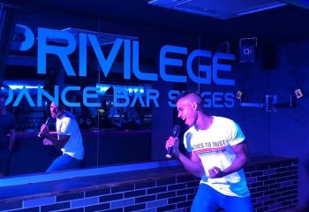 Vertigo Dance Bar, a gay club in Sitges. Man sings karaoke, reflected in a mirror. Nightlife, fun, and entertainment in Spain.