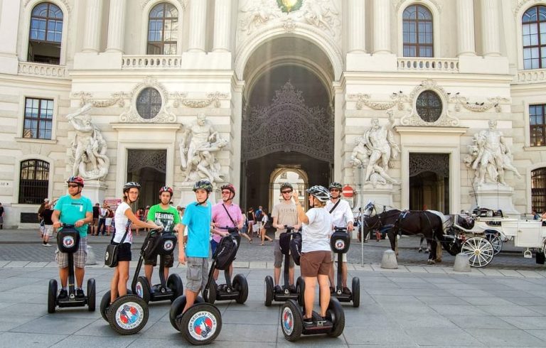 Vienna Segway Tour: Group of gay travelers on Segways exploring imperial hotspots, Hofburg Palace in background. Fun, eco-friendly sightseeing.
