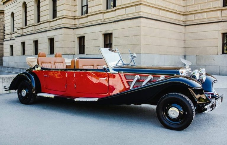 Vintage glam Prague private car tour. Classic red and black convertible car in front of a building. Gay travel advice.