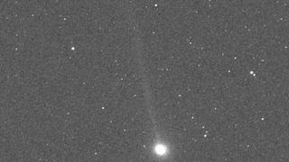 a bright white dot sits at the bottom center of a grainy grey image of space with smaller scattered stars.