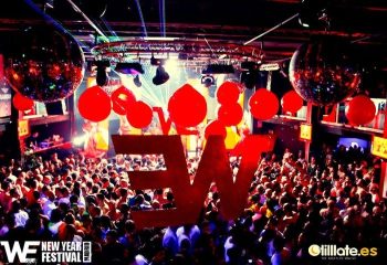 WE Party Madrid gay bar. Crowded dance floor with disco balls and red balloons. Gay nightlife in Madrid, Spain.