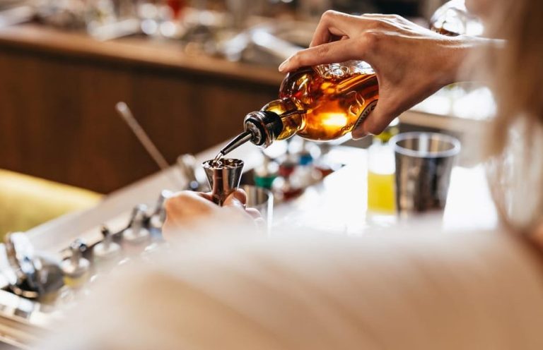 Roe & Co Distillery experience: Whiskey cocktail being poured into a jigger. Queer craft cocktail creation at distillery tour.