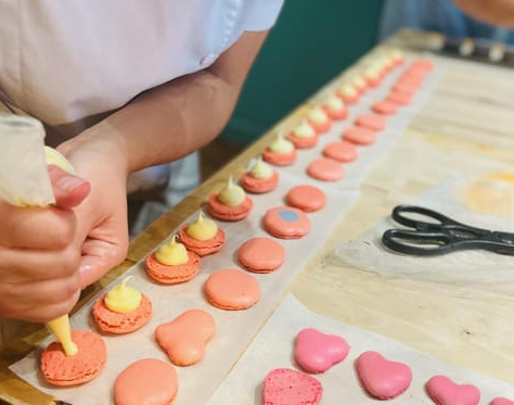 Gay-friendly French macaron masterclass: Chef fills macarons with cream. Parisian baking experience for gay men travelers.