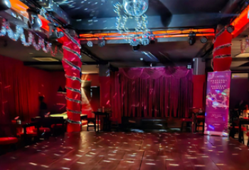 Blue Chilli gay bar in Phnom Penh. Stage with red curtains, disco ball, and red lighting. Gay travel advice for Phnom Penh nightlife.